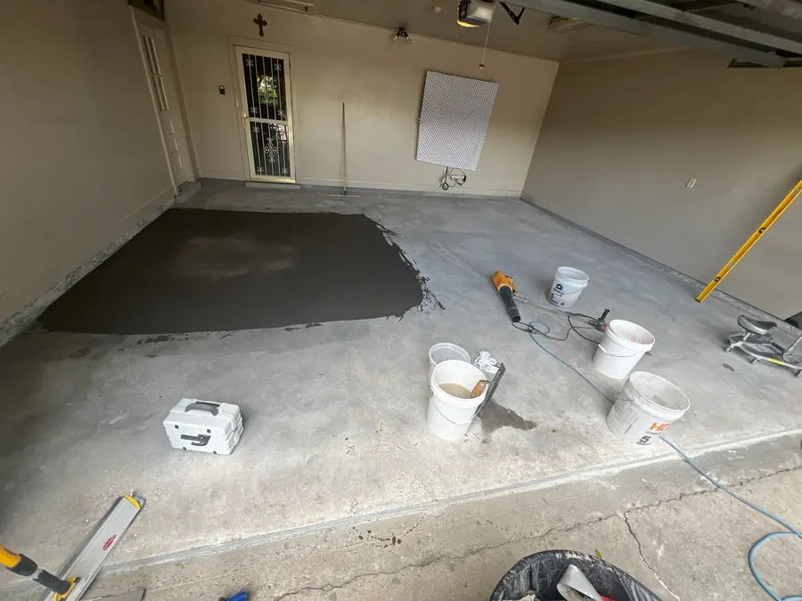 Garage floor mid-repair with patch compound and buckets