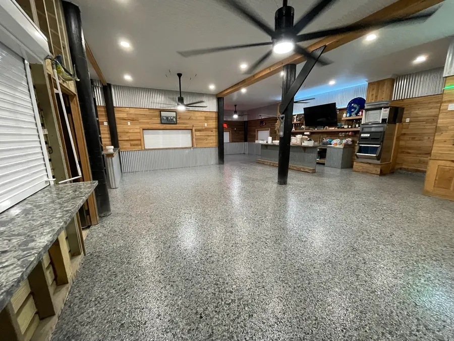 Grey flake floor through a rustic camp room with ceiling fans and a pine bar